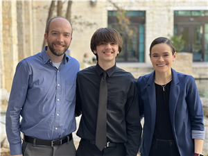 Man in blue shirt, boy in black shirt and black tie, woman in blue jacket, left to right